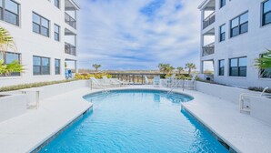 A modern building with a swimming pool, white exterior, and multiple balconies. - Bright and Spacious 3 bedroom ocean front, ground floor condo (St. Augustine Beach)