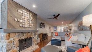 A living room with a stone fireplace, a grey sofa, and a ceiling fan. - Prospector Top Floor - Slps up to 10 - Pool/Hot Tub On Site (Park City)