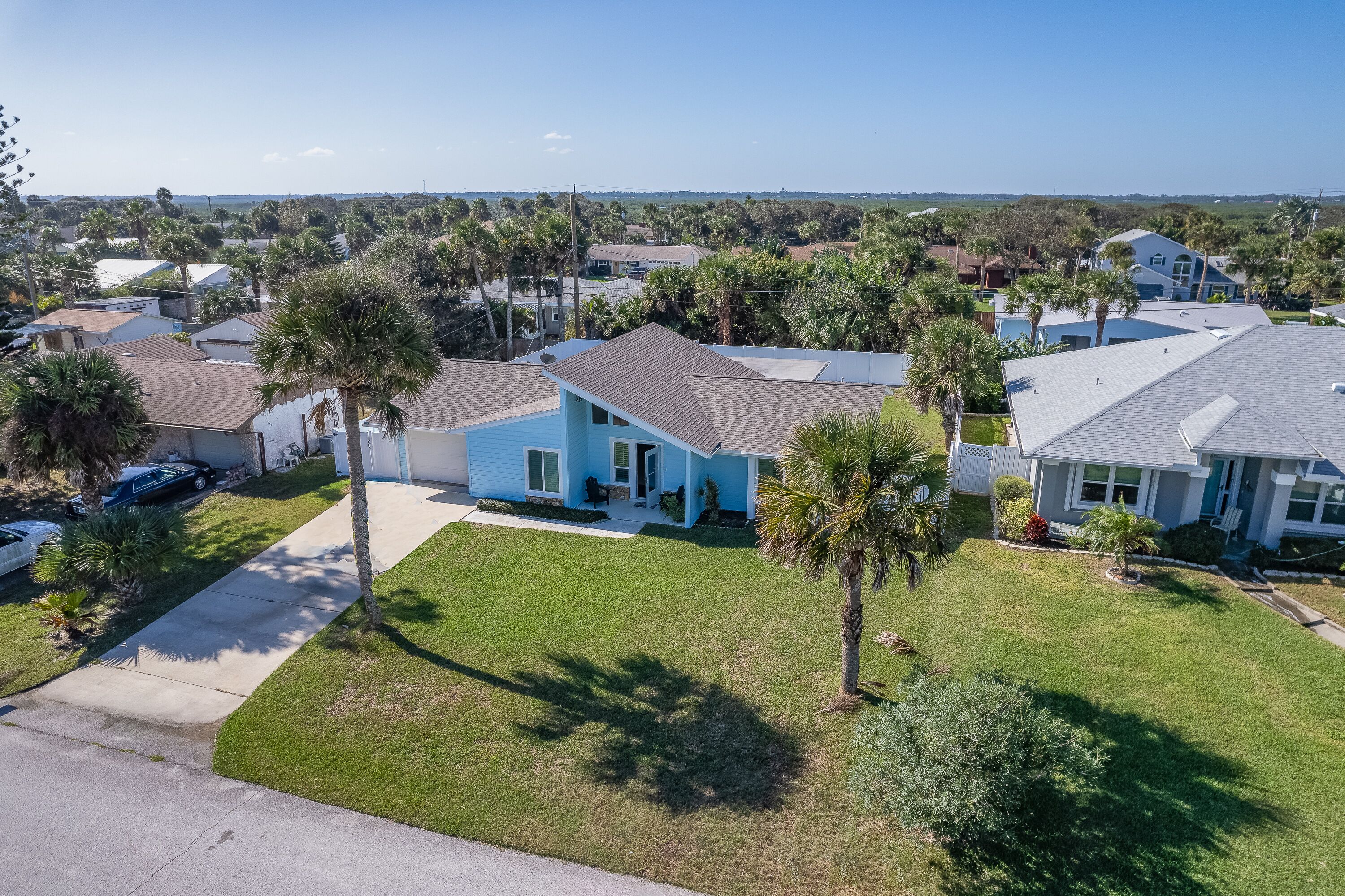 A residential area with houses, palm trees, and a clear sky.