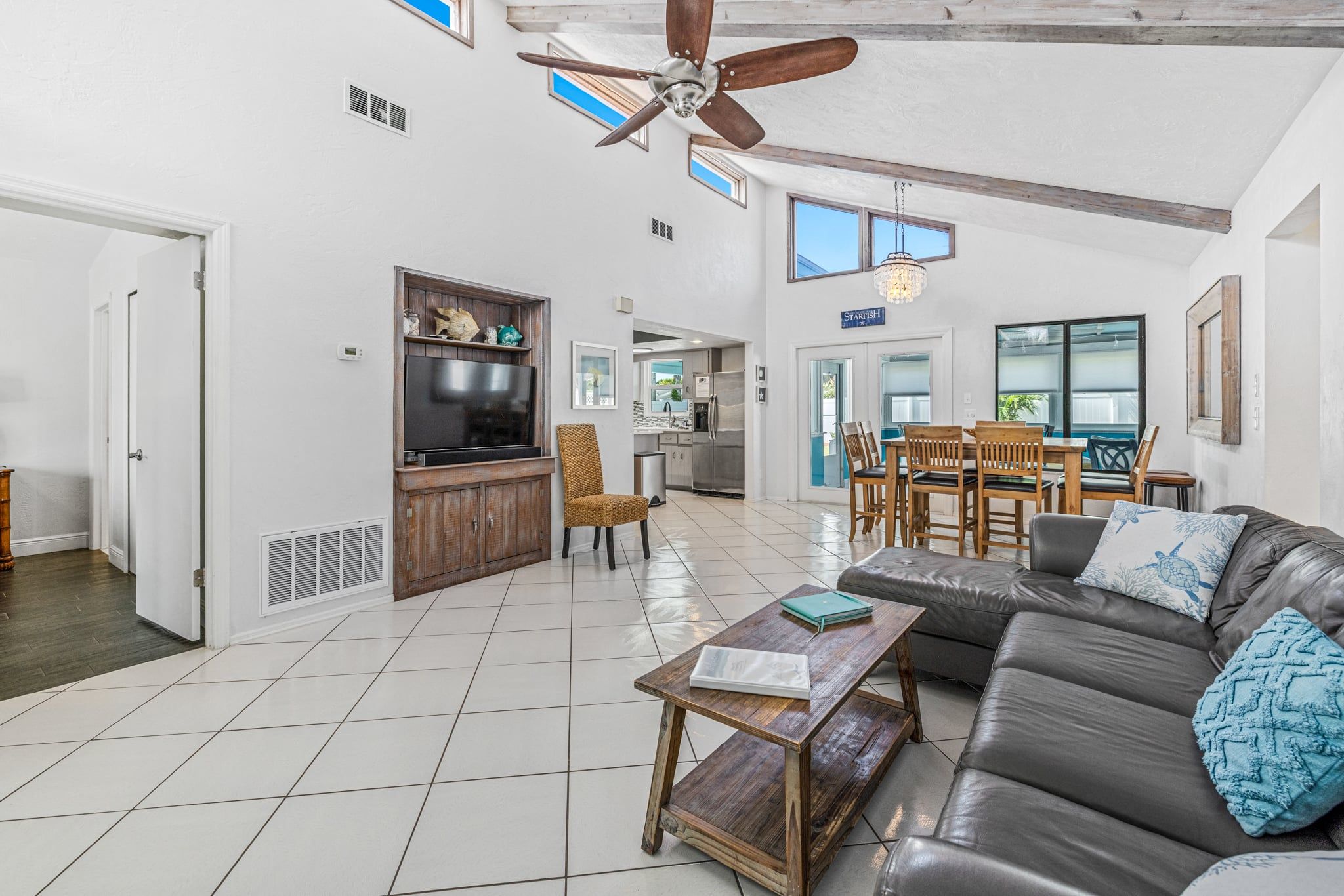 Spacious living room with vaulted ceiling, leather couch, and large Smart TV.