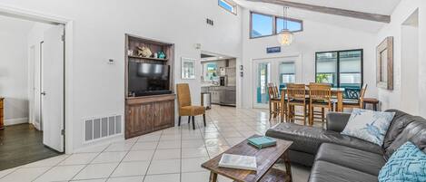 Spacious living room with vaulted ceiling, leather couch, and large Smart TV.
