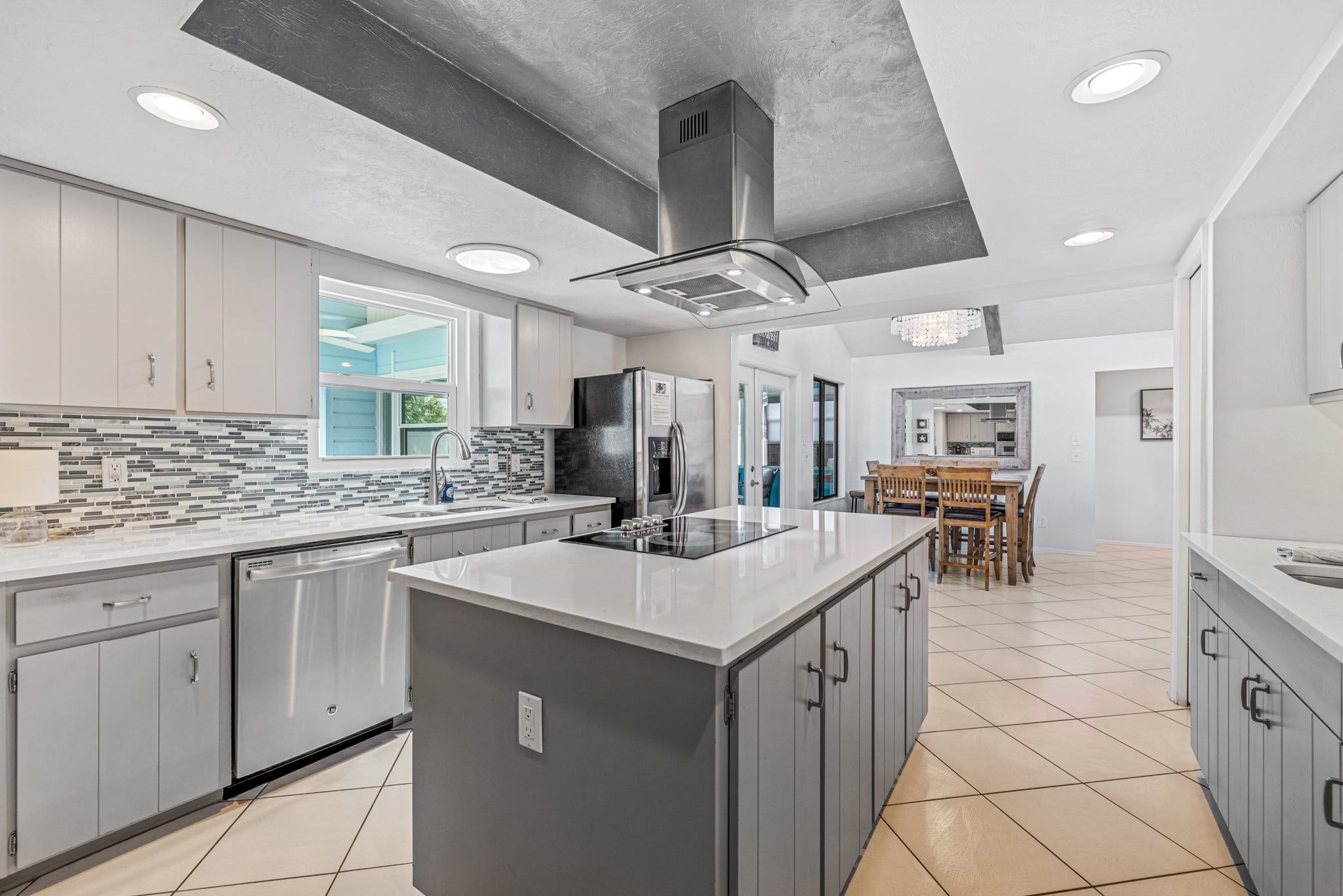 A modern kitchen with a large island, stainless steel appliances, and a tiled backsplash.