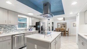 Una cocina moderna con electrodomésticos de acero inoxidable, una isla central y una zona de comedor con mobiliario de madera.