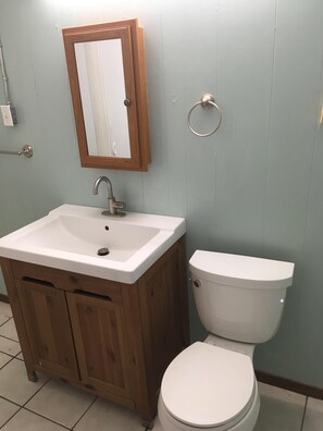 Een badkamer met een houten wastafel, een witte wasbak, een spiegel en een wit toilet.