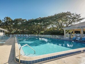 Une piscine rectangulaire dont la profondeur est indiquée par un repère à 3 pieds, entourée d’une clôture blanche, avec des chaises longues et un espace abrité d’un côté.