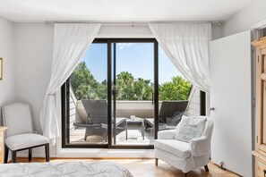 A bedroom with a large sliding glass door leading to a balcony with outdoor furniture. - Great Location! Walk to Beach, Club, Golf, Pools! Distant Ocean Views! Amenity access included! (Seabrook Island)