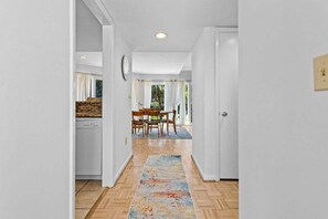 Un pasillo con zona de comedor, piso de madera y alfombra.