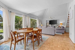 A spacious living area with a dining table, chairs, a sofa, and a television.