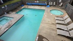 Una piscina rectangular con un trampolín y sillas de descanso.