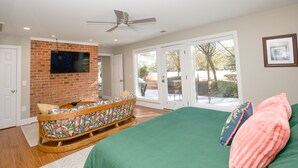 A bedroom with a green bed, a rocking chair, a ceiling fan, and a large window. - Loblolly's Pinehurst No. 3 Retreat on the 11th Fairway! (Pinehurst)
