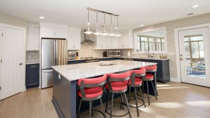 A modern kitchen with a central island, stainless steel appliances, and a bright pendant light fixture. - Loblolly's Pinehurst No. 3 Retreat on the 11th Fairway! (Pinehurst)