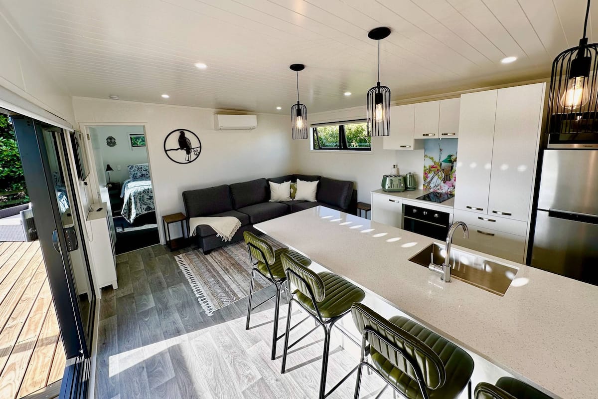 A modern kitchen with a central island, bar stools, and a built-in oven.