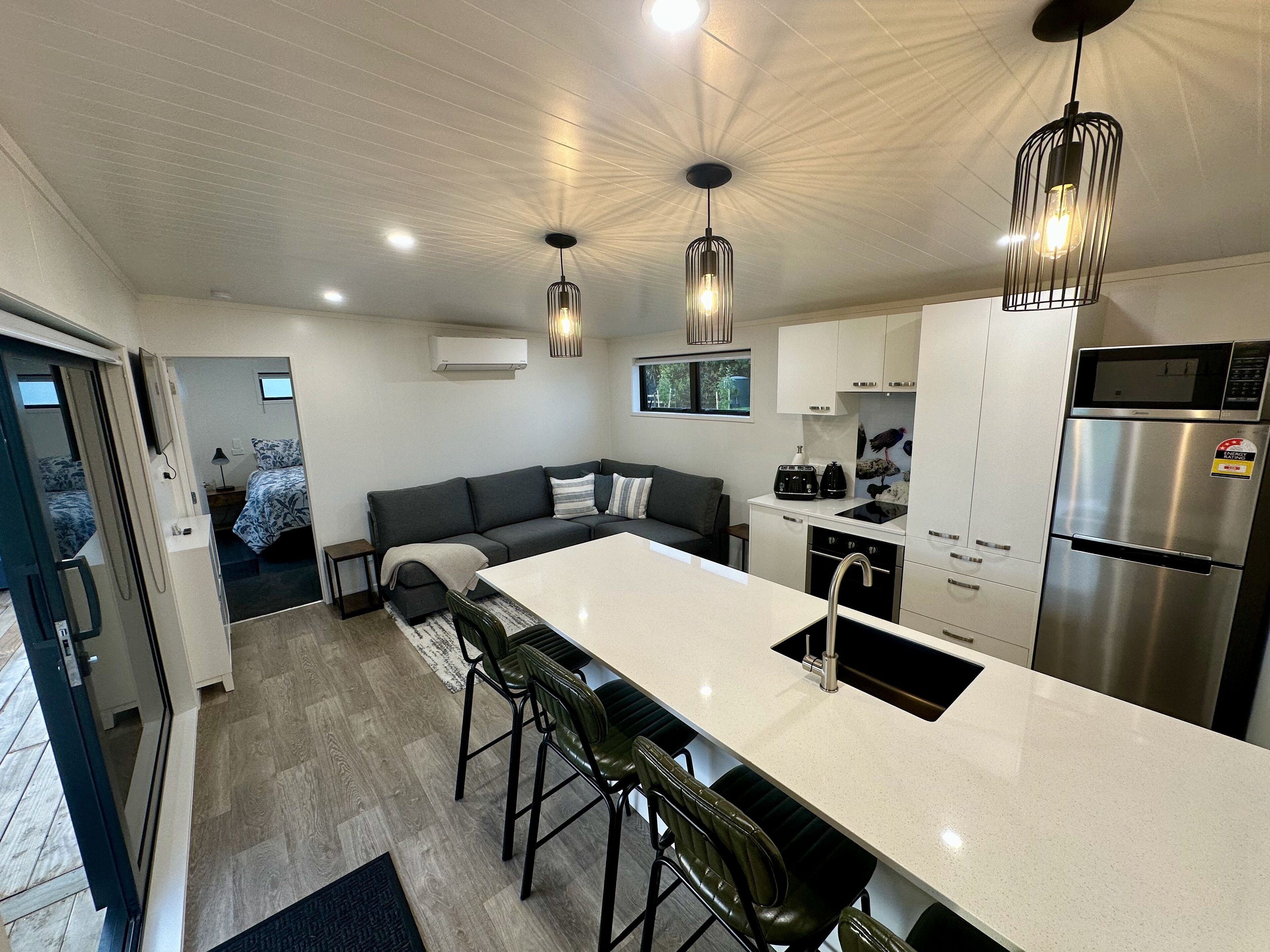 A modern kitchen with a central island, bar stools, a built-in oven, and a refrigerator.