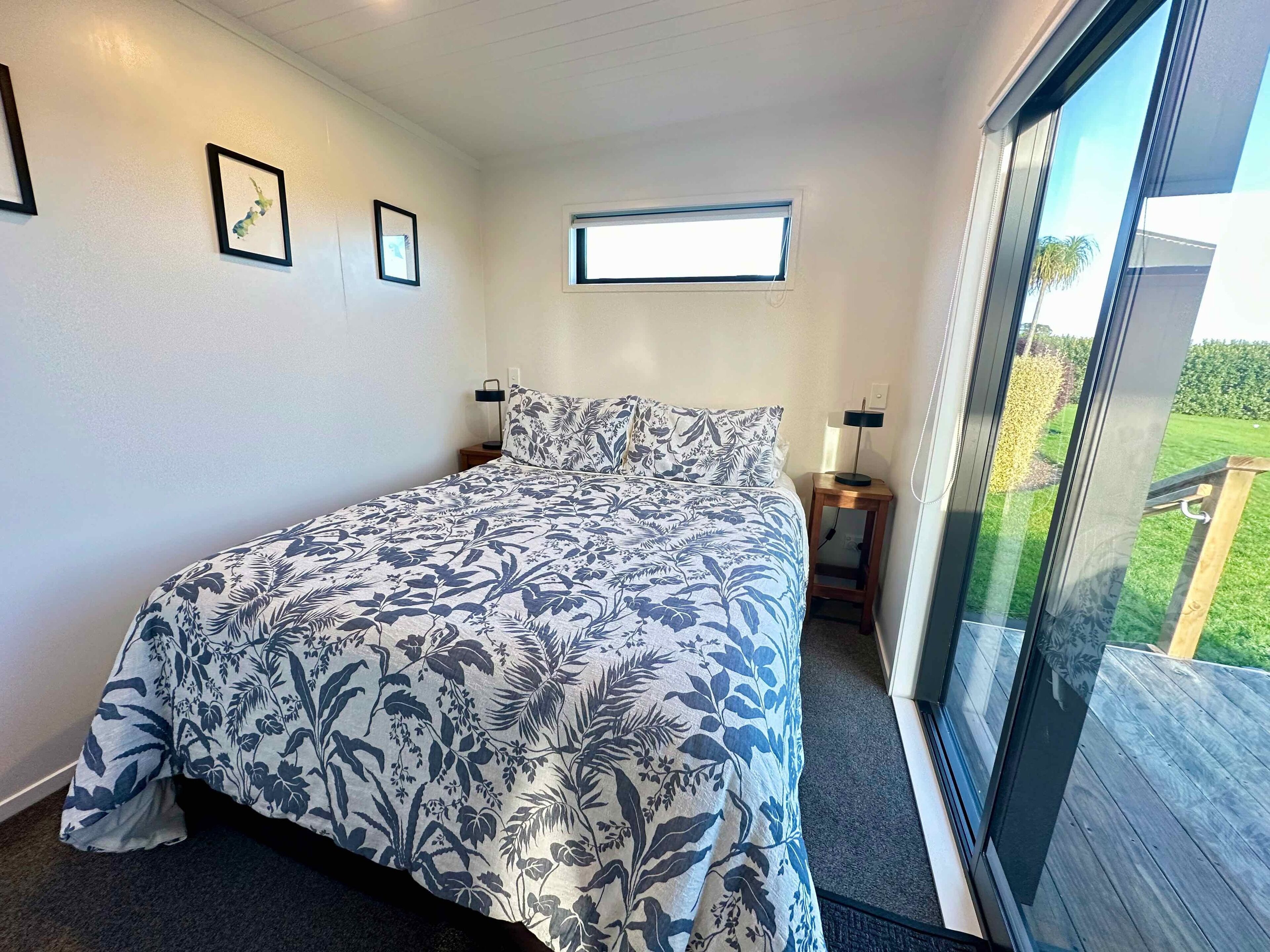 A bedroom with a large bed, a window, and a view of a deck.