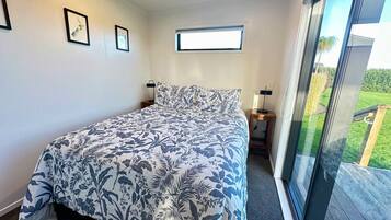 A bedroom with a large bed, a window, and a view of a deck.