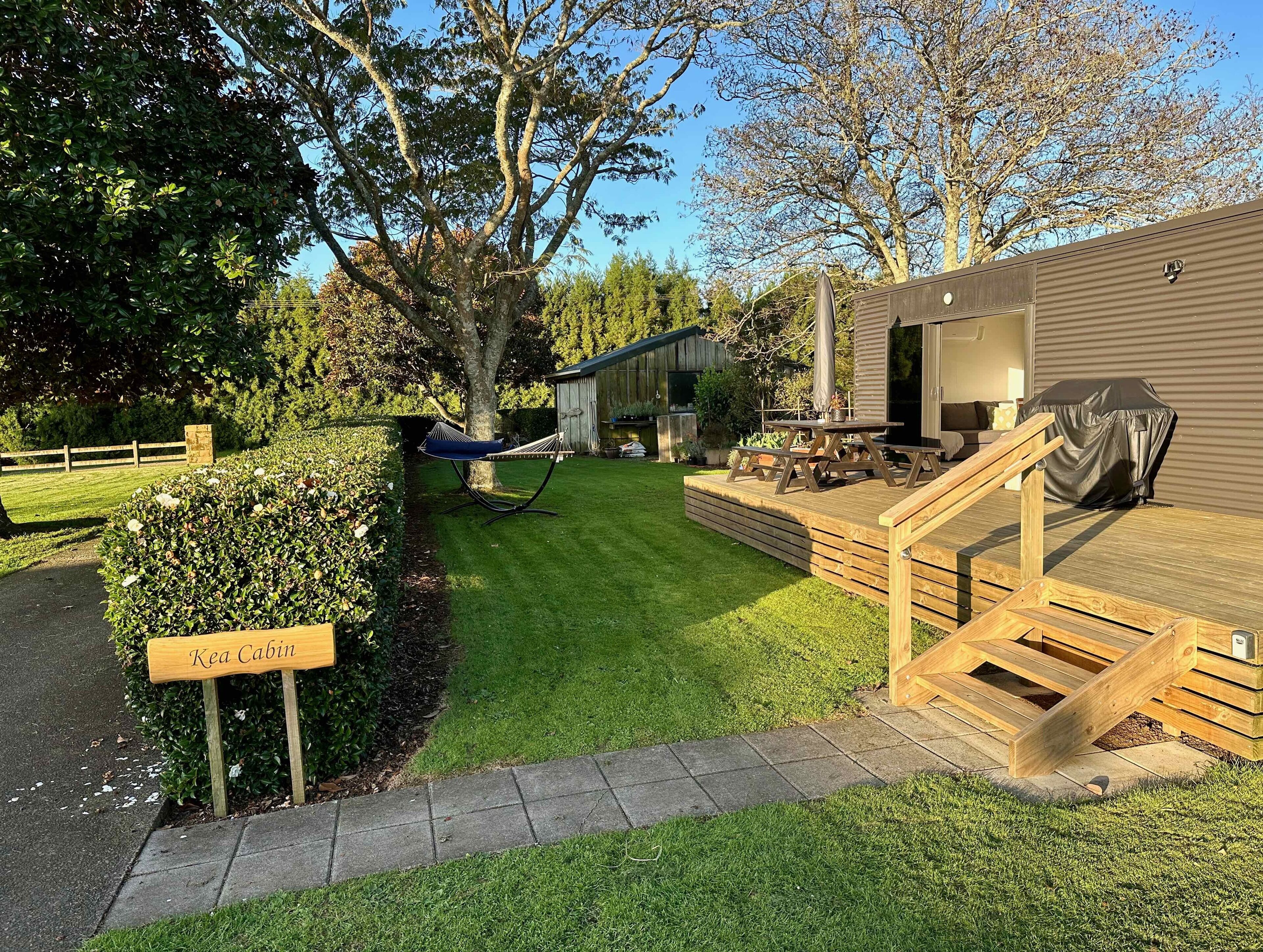 Un jardin bien entretenu, agrémenté d’un hamac, d’une terrasse en bois et d’une pancarte indiquant « Kea Cabin ».
