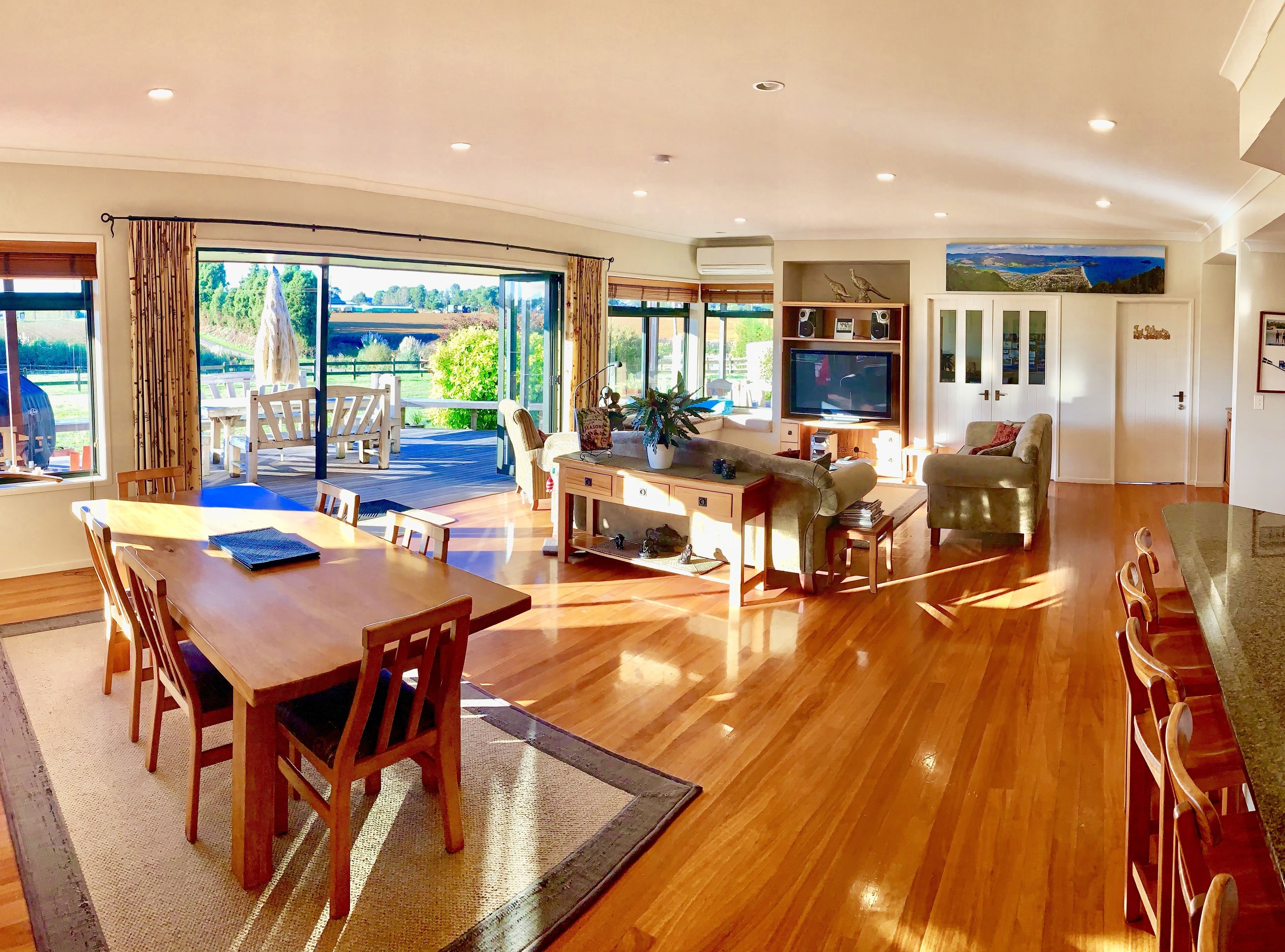 A spacious living area with a wooden dining table, a sofa, and a TV.