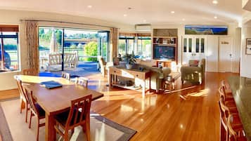 A spacious living area with a wooden dining table, a sofa, and a TV.