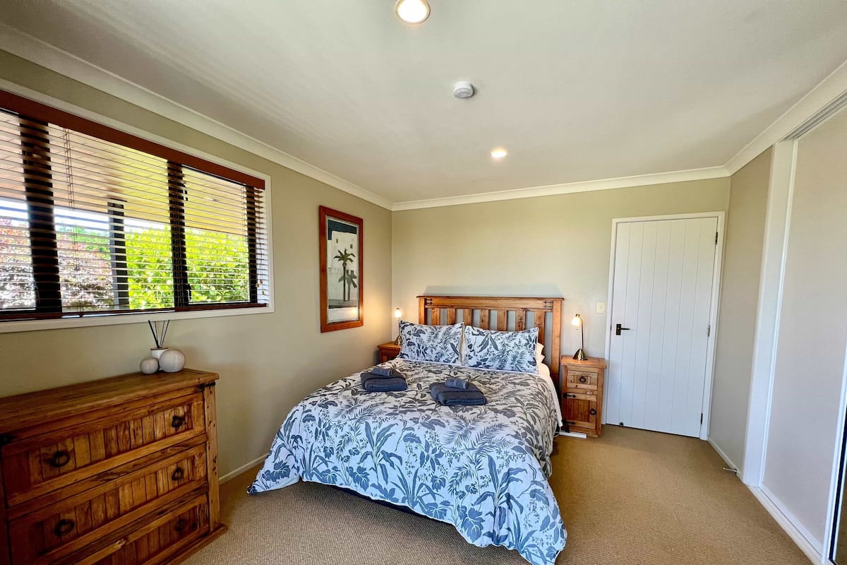 A bedroom with a bed, wooden dresser, and a door.