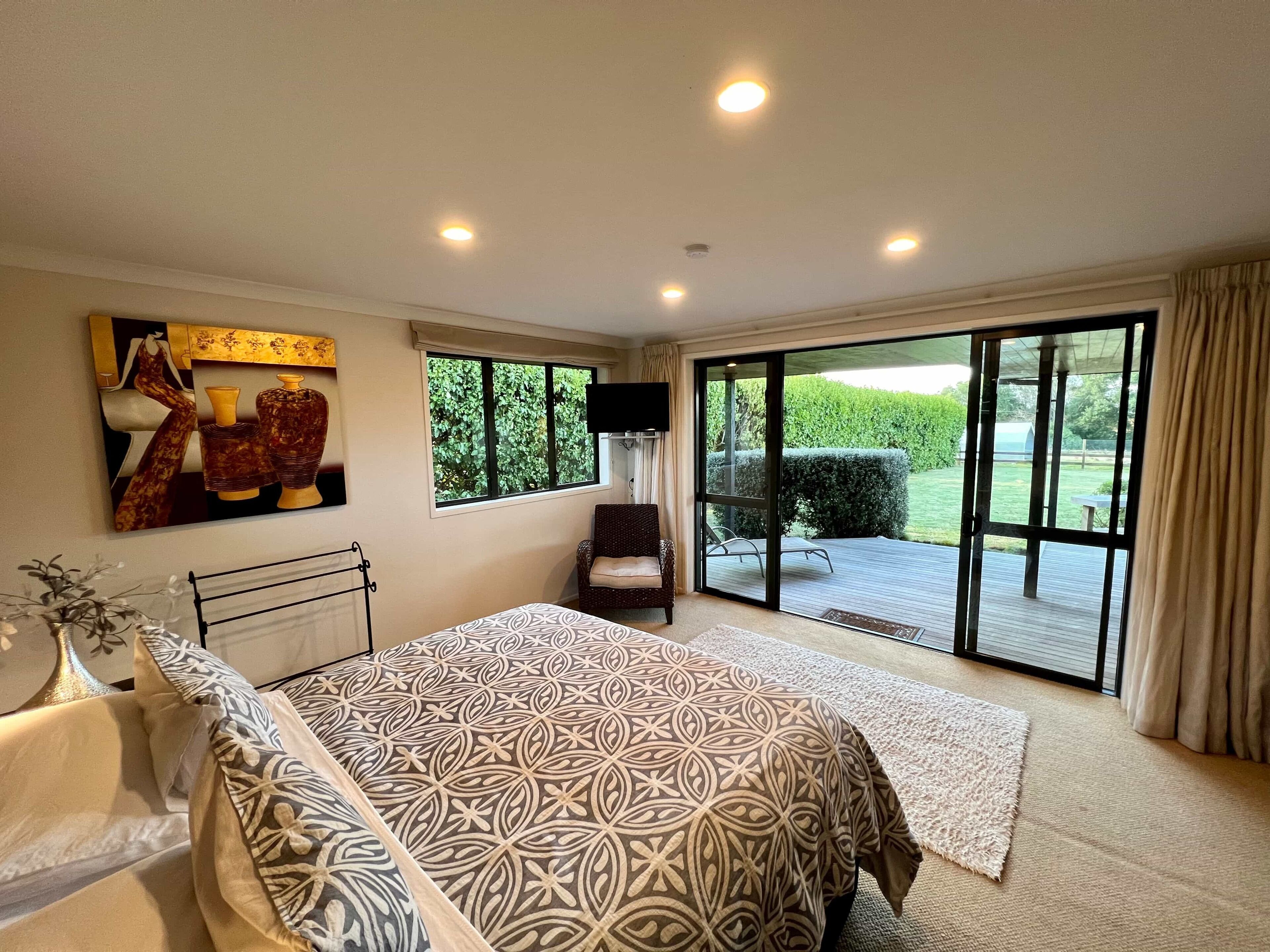 A bedroom with a large bed, a television, a window, and a sliding glass door leading to a patio.