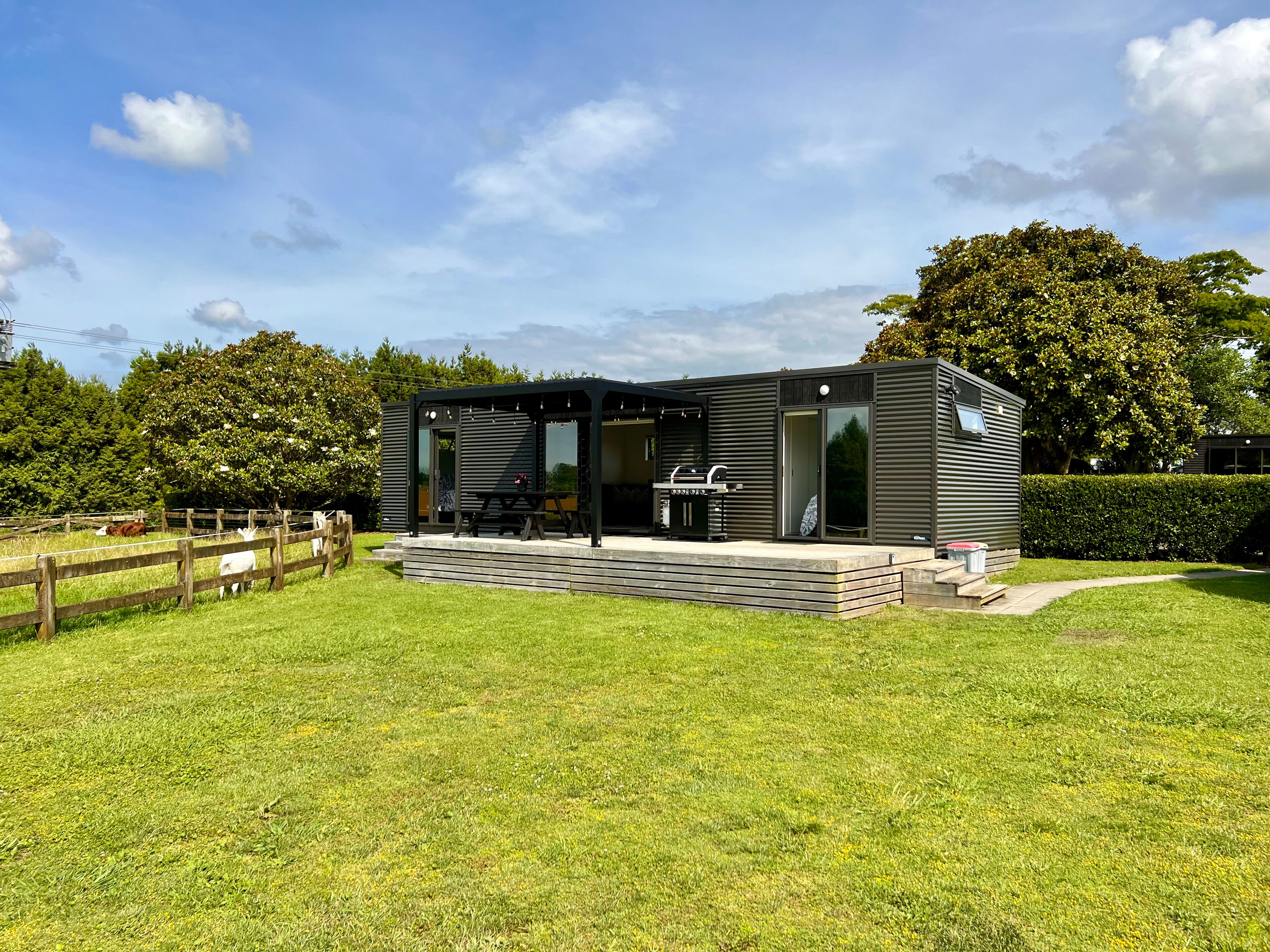 Una casa moderna dai colori scuri con patio, area barbecue e giardino recintato.