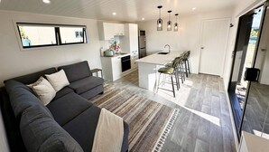 A modern kitchen with white cabinetry, a central island, and bar stools. - Heaven's Rest B&B (Bombay)