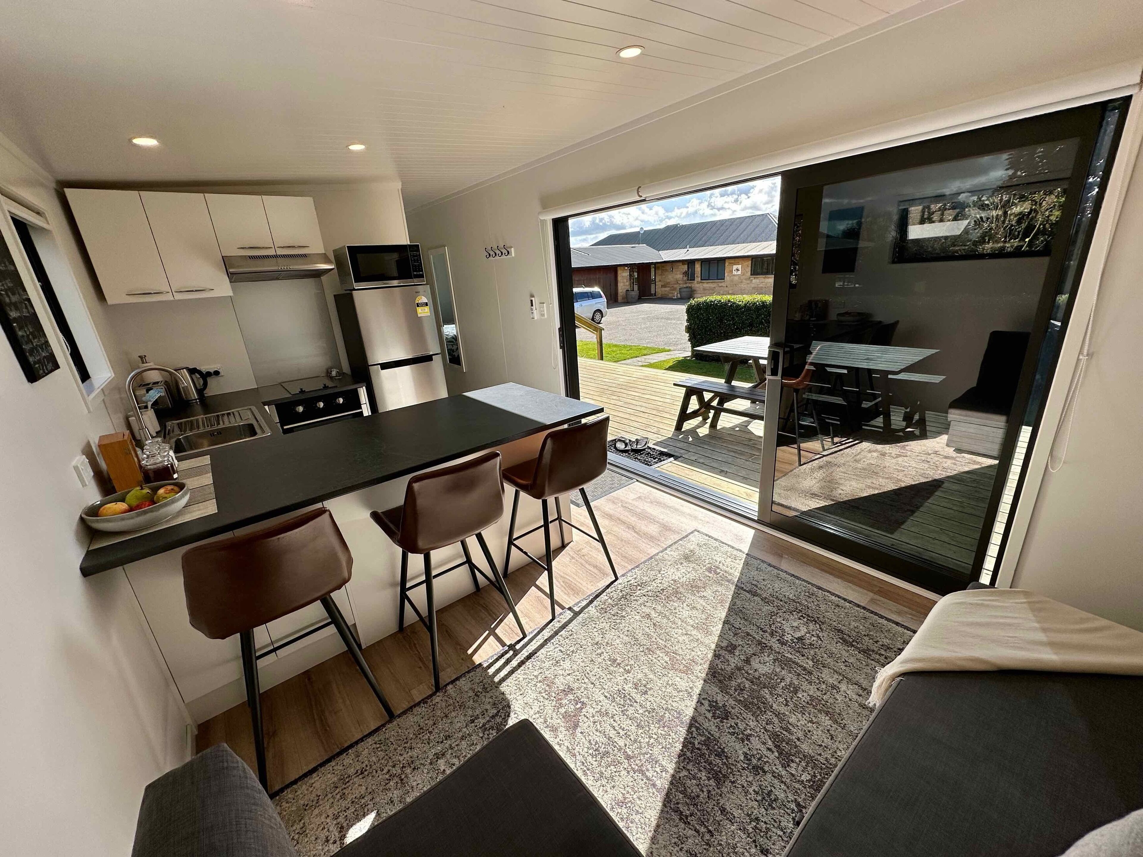 Una cocina compacta con electrodomésticos modernos, una zona de comedor con un banco y vistas al exterior.