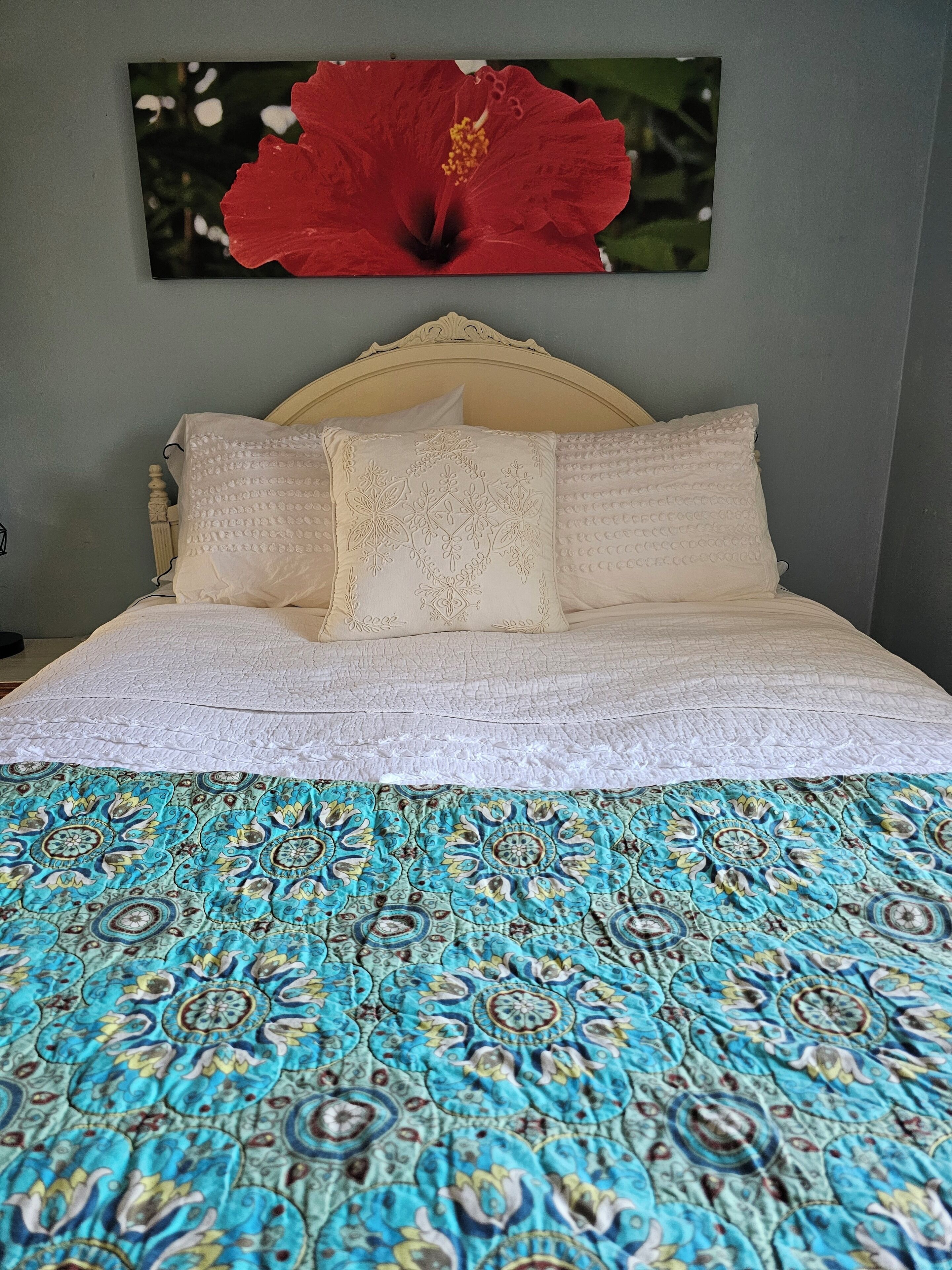 A bed with a patterned bedspread, two pillows, and a headboard.