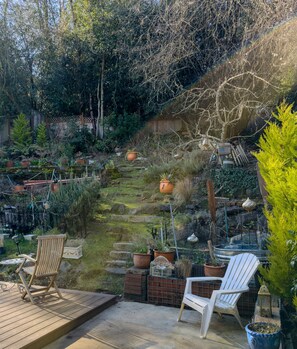 A garden with a wooden deck, two Adirondack chairs, and various potted plants. - 2 BEDROOM HIDEAWAY BY DISCOVERY PARK, FAMILIES, COUPLES, SOLO STAYS (Seattle)
