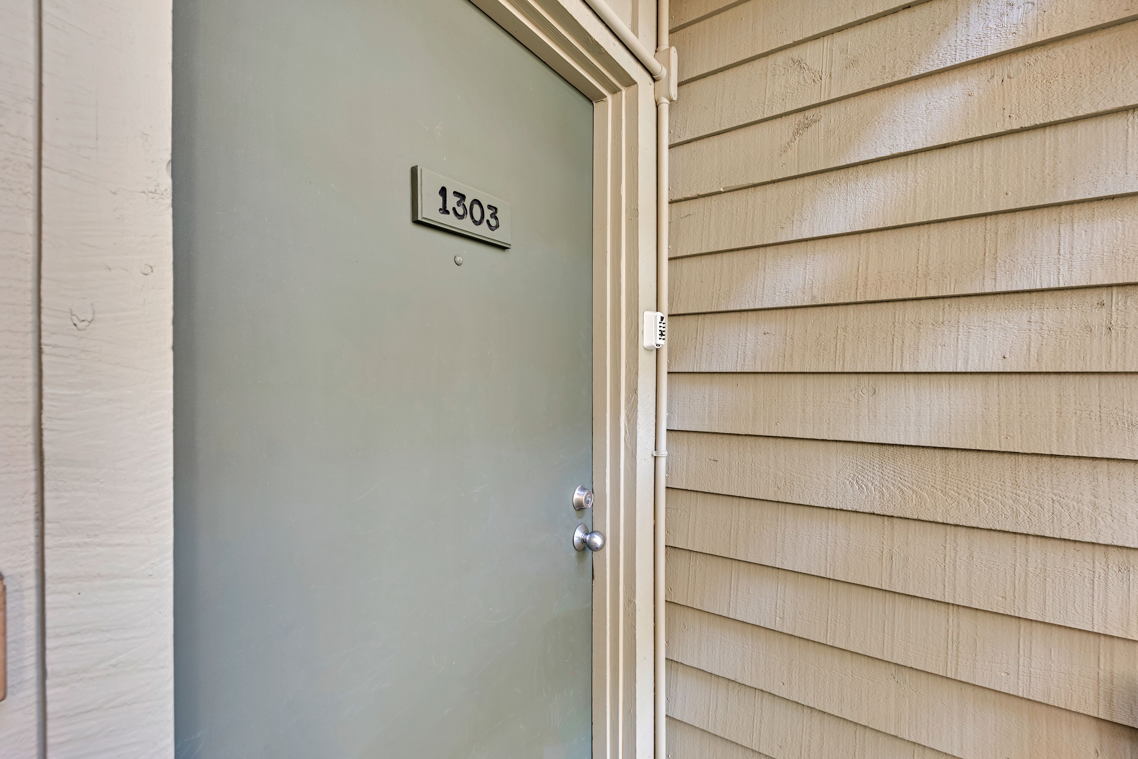 A door with a number plate '1303' and a doorbell.