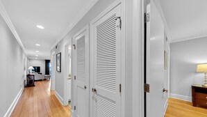 Un pasillo con puertas blancas, pisos de madera e iluminación empotrada.