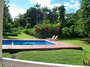 Relax by the serene pool surrounded by lush greenery and comfortable lounge chairs.