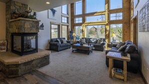 Un salón comedor amplio con chimenea de piedra, ventanas grandes y muebles modernos.