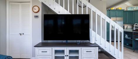 A living room with a white entertainment center, a flat-screen TV, and a staircase with white railings.