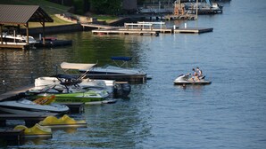 Un puerto deportivo con varias embarcaciones amarradas, incluyendo un jet ski y un barco rápido.