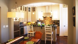 Una cocina con una mesa de comedor para cuatro personas, una araña y un salpicadero de azulejos.