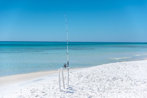 A beach with a fishing rod set up on the sand.