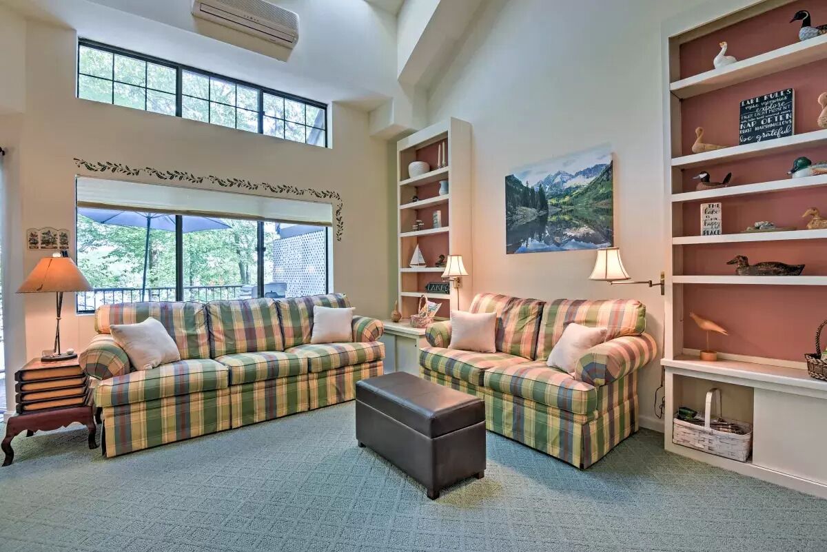 A cozy living room with two plaid sofas, a coffee table, and a bookshelf filled with decorative items.