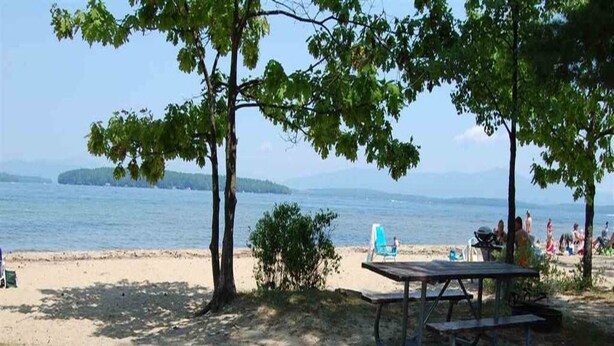 A beach with a picnic table, a grill, and a fire pit.