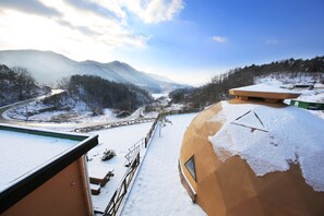 A snow-covered landscape with a curved building and a road curving through the valley.