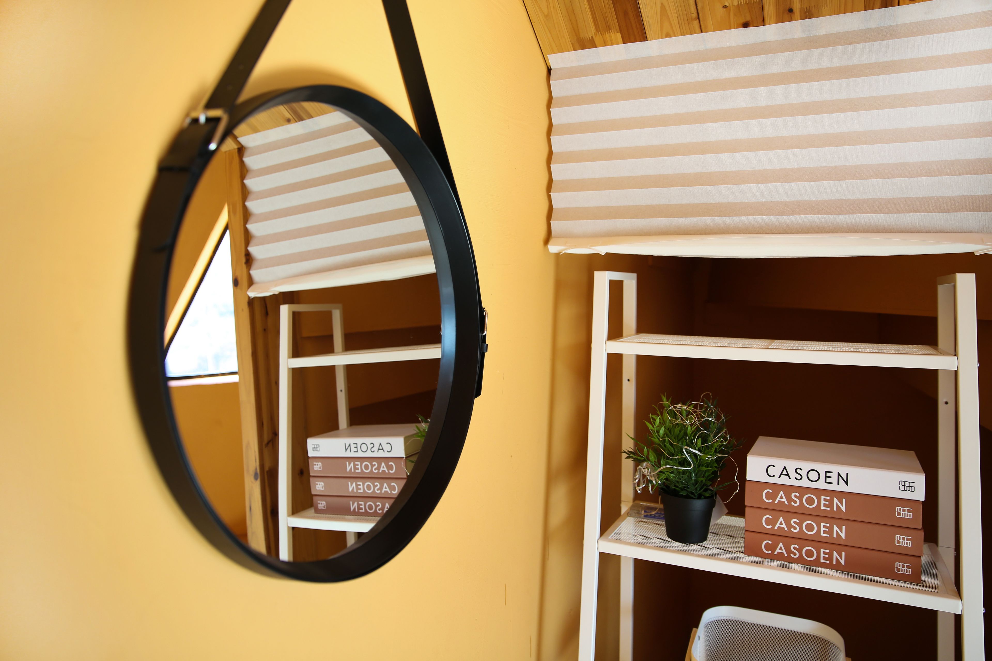A room with a mirror, a striped awning, and shelves with boxes labeled "CASOEN".