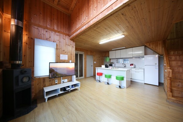 A cozy wooden cabin interior with a TV, kitchen, and bar area.