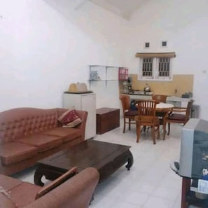 A living room with a sofa, a coffee table, and a dining area with a table and chairs.