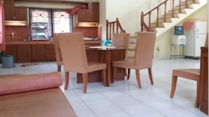 A spacious living area with a dining table and chairs, a sofa, a kitchen with wooden cabinets, and a staircase. - Villa Sasky Ciater Highland (Ciater)