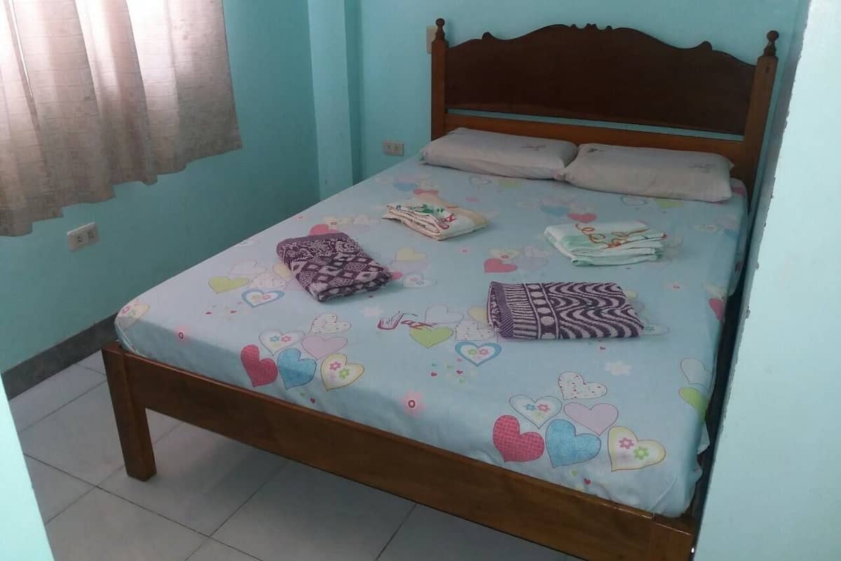A bed with a patterned bedspread, pillows, and folded blankets.