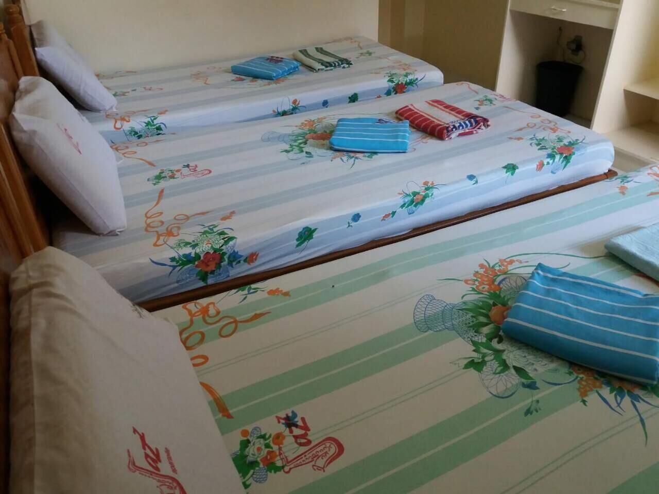 A room with two beds, each with floral-patterned bedding and pillows.