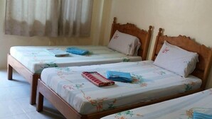 Een kamer met drie houten bedden, elk voorzien van beddengoed en kussens met een bloemenprint.