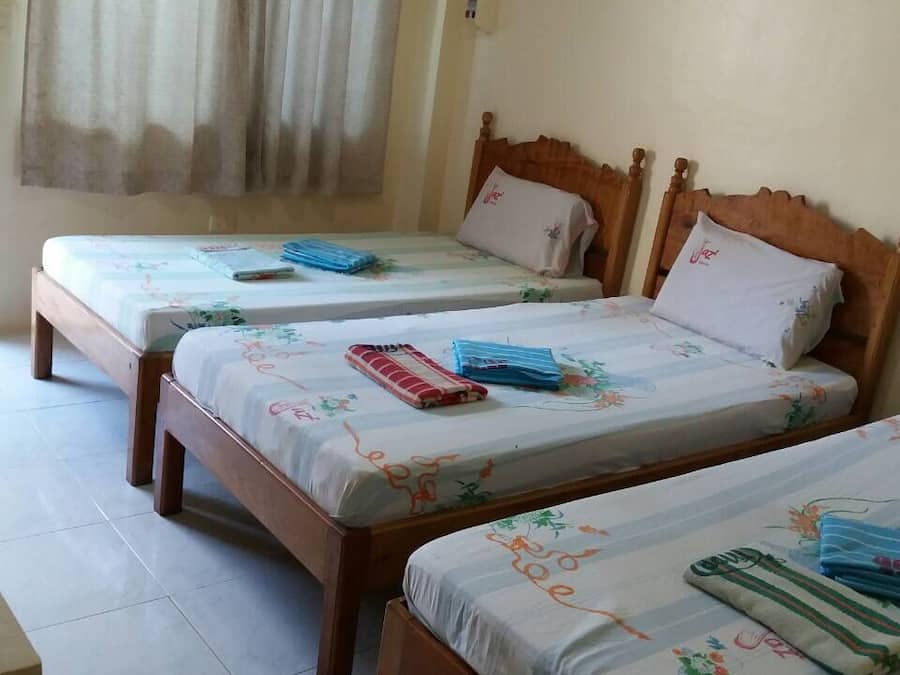 A room with three wooden beds, each with a floral bedspread and pillows.