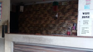 Een receptiegedeelte met een gesloten luik, een prullenbak en een bordje dat een WiFi-zone en een kamer in reparatie aangeeft.