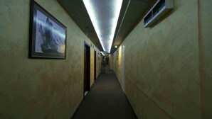 A narrow hallway with framed pictures on the walls, a ceiling light, and air vents. - Hotel Alabin Central (Sofia)